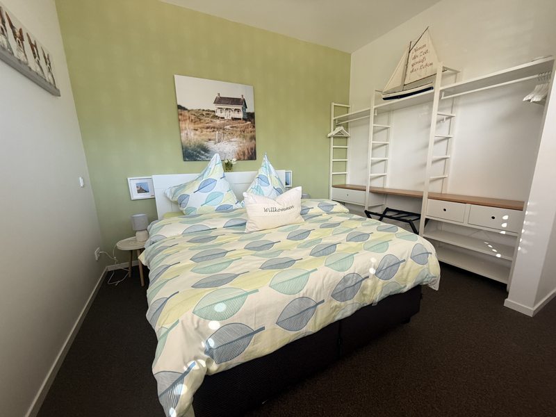 Schlafzimmer mit Doppelbett und offener Garderobe